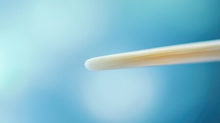 Close up of a toothpick against a soft blue background with a blurred effect