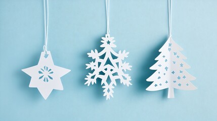 Paper cut-out ornaments shaped like Christmas trees and stars, on a soft blue background