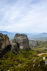 Meteroa, Greece. Majestic rock formations in rise dramatically from the landscape, offering a glimpse into nature's grandeur against the backdrop of distant snow-capped mountains