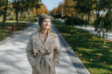 Stylish woman in trench coat with golden leaves background