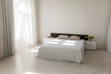Bed by the window in the interior of a white bedroom