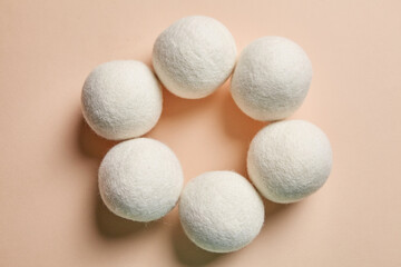 Six wool dryer balls arranged in a circular formation on a beige background. Eco-friendly and...