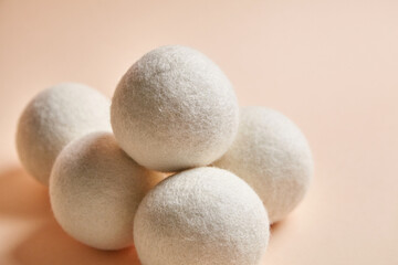 Close-up of wool dryer balls arranged in a cluster on a light beige background. Eco-friendly, reusable solution for reducing static, wrinkles, and drying time