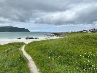 Breathtaking landscape of Norway's Lofoten Islands, with towering mountains and the serene Arctic Ocean. A stunning display of natural beauty and rugged coastal charm.