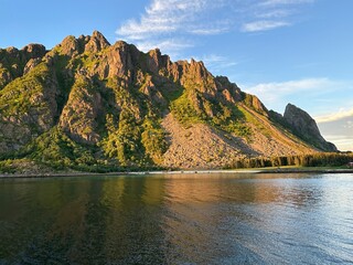 Panoramic view of Norway's Lofoten Islands under the midnight sun. Golden light illuminates...