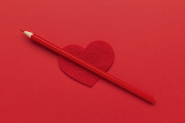 Red Pencil on Heart-Shaped Cutout: Symbol of Love and Creativity on Bold Red Background