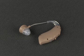 Modern Beige Hearing Aid Device on Dark Background for Hearing Assistance