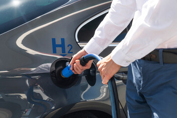Man holds a hydrogen fueling nozzle on a hydrogen filling station. Refueling car with hydrogen fuel.