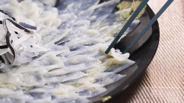 日本料理 ふぐ刺しを箸でつかむ