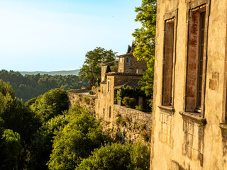 Fototapeta premium Glimpse of Menerbes in France Provence, with stone houses on the right overlooking the leafy valley below in the warm light of sunset. 