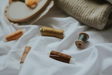 beige shades of thread with needles against the background of delicate colors of fabrics 