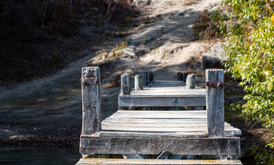 Wooden jetty bridge in the water calm clear lake Hayes New Zealand