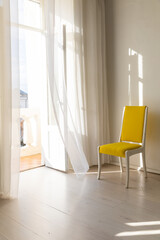 Yellow vintage chair in the interior of an empty white room with a window