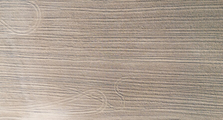 Aerial view of a plowed agricultural field with patterned soil lines, showcasing agricultural...