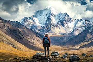 Obraz premium Lone hiker stands in awe of a breathtaking, snow-capped mountain peak, surrounded by the vast wilderness, embracing the tranquility and grandeur of nature