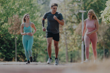 Three friends exercising together in the park on a sunny day, enjoying outdoor fitness and companionship. They are jogging and staying active in a natural setting.