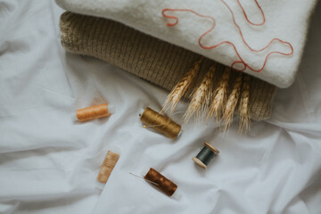 beige shades of thread with needles against the background of delicate colors of fabrics 