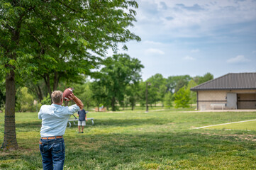 Grandpa playing catch with a football at a park