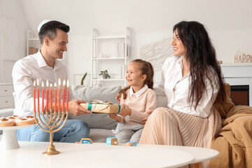 Happy family celebrating Hanukkah with gift at home