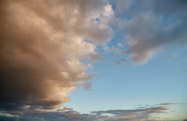 Obraz premium Blue-pink clouds in the evening sky, cumulus clouds illuminated by the setting sun, dense cloud cover in the sky.