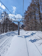 Obraz premium View of a dual ski chairlift at a Japanese ski resort on a sunny winters day