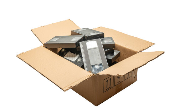 A box full of old VHS tapes. The box is open and the tapes are scattered inside