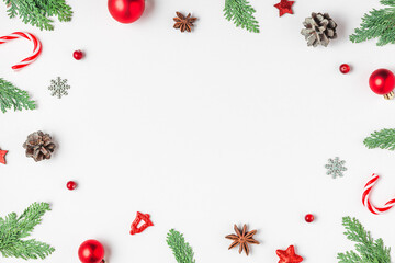 Christmas frame made of fir branches, red decorations, candy and pine cones isolated on white background. Flat lay. Happy New Year and winter holidays background. Top view