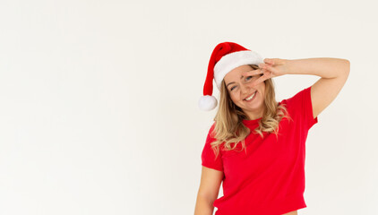 Cheerful pretty young brunette Santa woman wearing red t-shirt Christmas hat showing victory sign isolated on white colour background, studio portrait. Happy New Year holiday concept