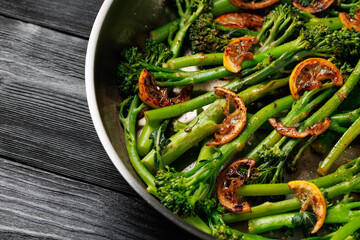 Tenderstem broccoli and charred lemon served in stainless steel frying pan