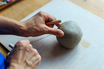 hands mold a clay ball, hands of ceramist