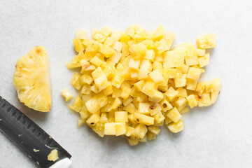 Top view of diced pineapples on a marble countertop, overhead view of chopped pineapples on a white...