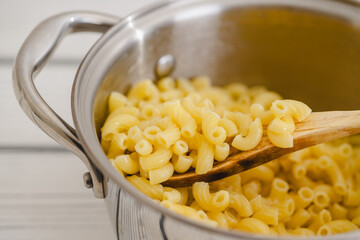 Cooked pasta in a pot. Elbows pasta in a cooking pot close-up on a table