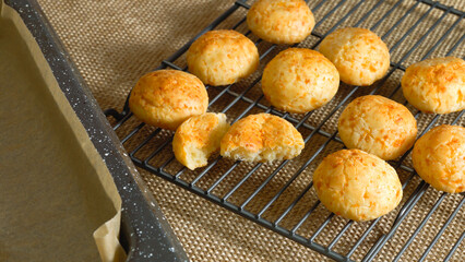 Traditional Brazilian cheese bread balls on cooling rack close-up on rustic background