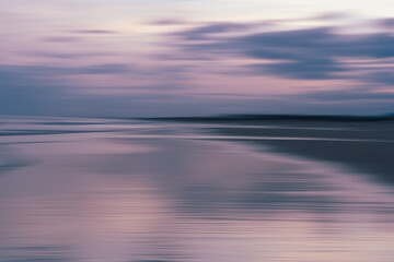 Gentle waves rolling toward the shore under a pastel-colored sky, abstract sea