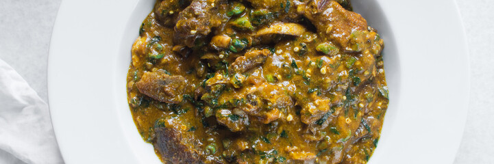 Overhead view of nigerian ogbono soup in a white plate, top view of ogbono draw soup with assorted meats in a soup plate, flatlay of nigerian ogbono and okra soup