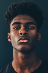 Obraz premium Bold Portrait of a Young Man with Dramatic Lighting and Moody Navy Background