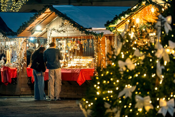 Illuminated Christmas tree and wooden kiosks at the Christmas market in Asti, Italy.