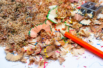 Colorful pencil shavings and sharpened tools scattered across a workspace filled with creative...