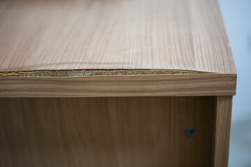 Chipboard table with delaminated edge due to humidity. Wooden surface care.