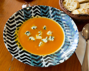 Vegetarian concept. Carrot cream soup served in plate with soft cheese gorgonzola..