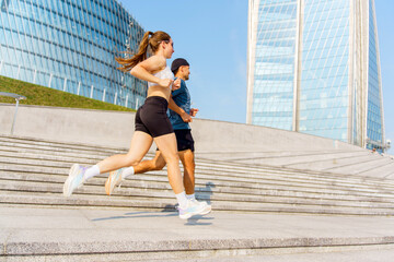 Young Athletes Jogging on Urban Steps During Bright Daylight Near Modern Skyscrapers in the City