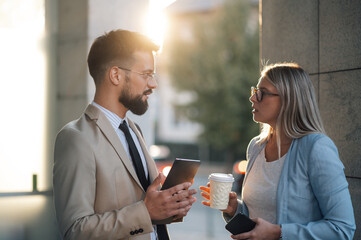 Business people having conversation on city street during coffee break