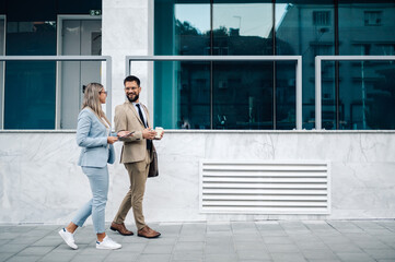 Two business partners walking outside office building and having discussion