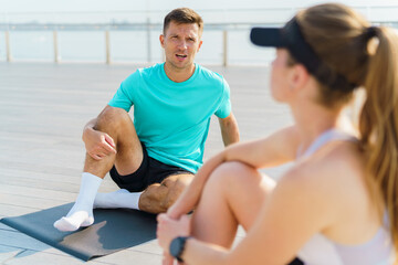 A Man and Woman Converse While Exercising Outdoors on a Sunny Day at a Waterfront Location