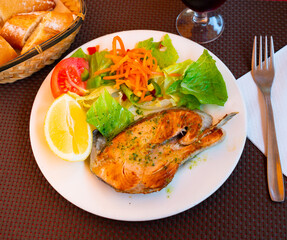 Appetizing baked salmon with fresh salad and vegetables served on platter