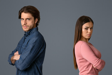 Break Up. Offended man and woman standing back to back with folded arms on light studio background and looking at camera, free space
