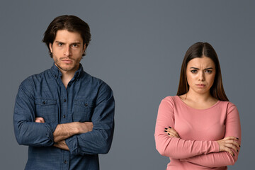 Millennial couple suffering from relationship problems, standing together offended after quarrel over light background in studio, free space