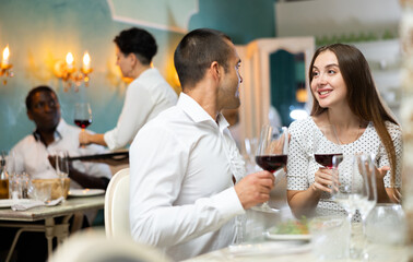 Young couple having romantic dinner and drinking red wine at restaurant