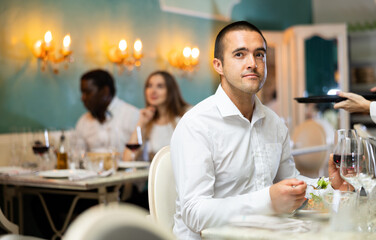 Portrait of man with glass of red wine waiting for woman in a restaurant