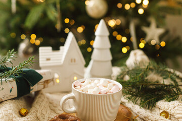 Warm cup of cocoa with marshmallows and chocolate cookies on wooden tray, christmas ornaments and...
